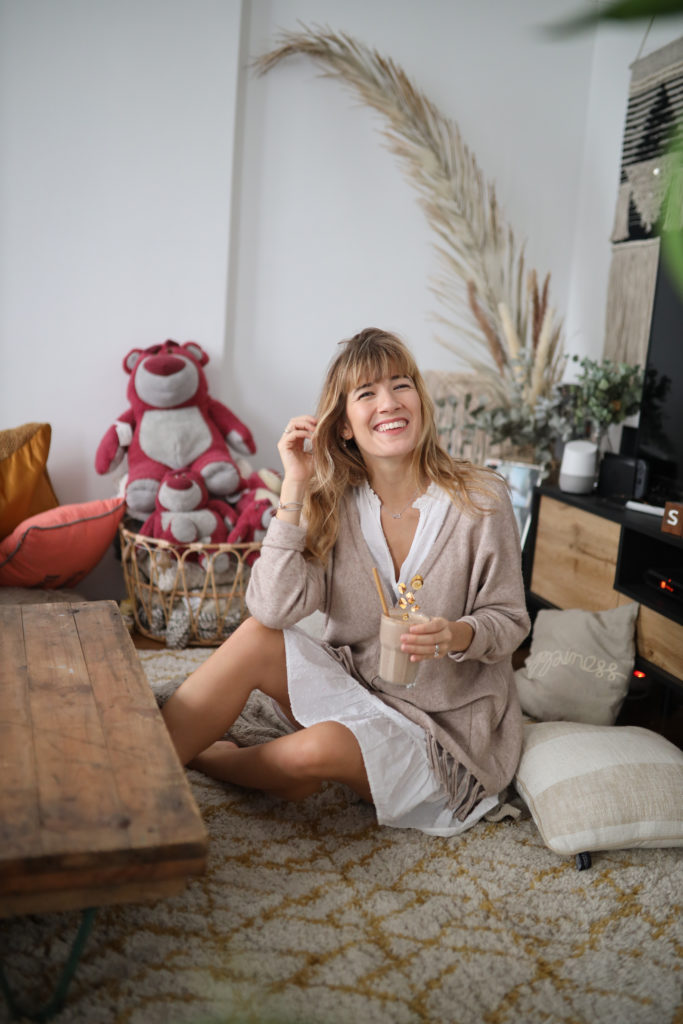 jeune femme dégustant un smoothie banane, fruits rouges, amande, dattes, healthy et gourmand à la maison qui rigole